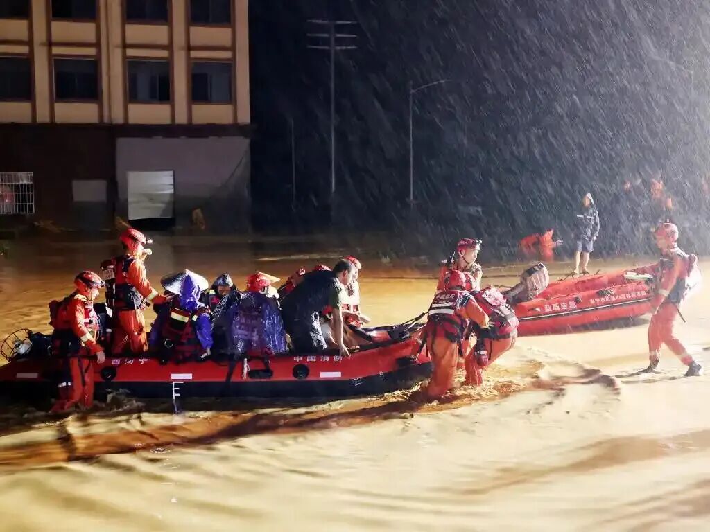 救援队员在暴雨洪水中转运群众